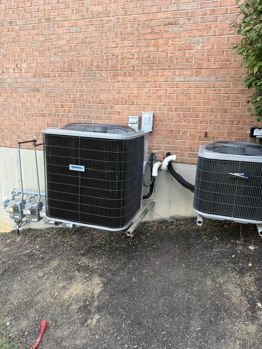 Tempstar outdoor air conditioner installed next to an existing condenser